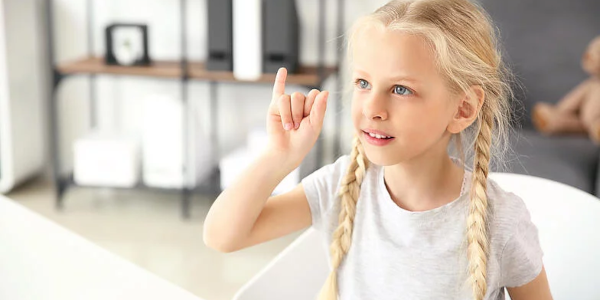 Ein Kind mit langen blonden Haaren spricht Gebärden