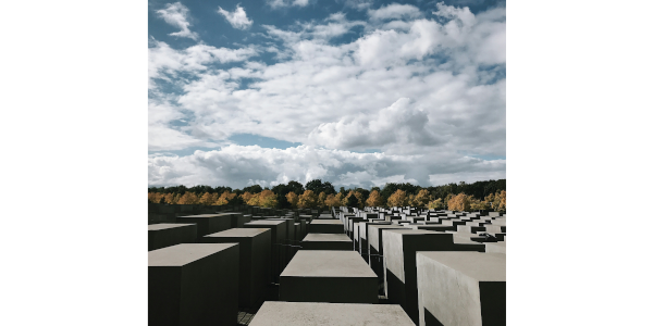 Bild des Denkmals für die ermordeten Juden Europas. unterschiedlich hohe Betonblöcke vor blauem Himmel mit Wolken.